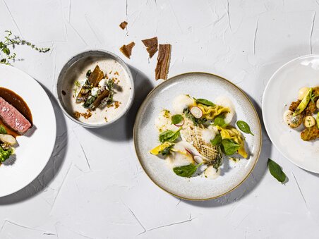 Four artfully arranged plates with various dishes. | © Restaurant Schlossberg - Werner Krug