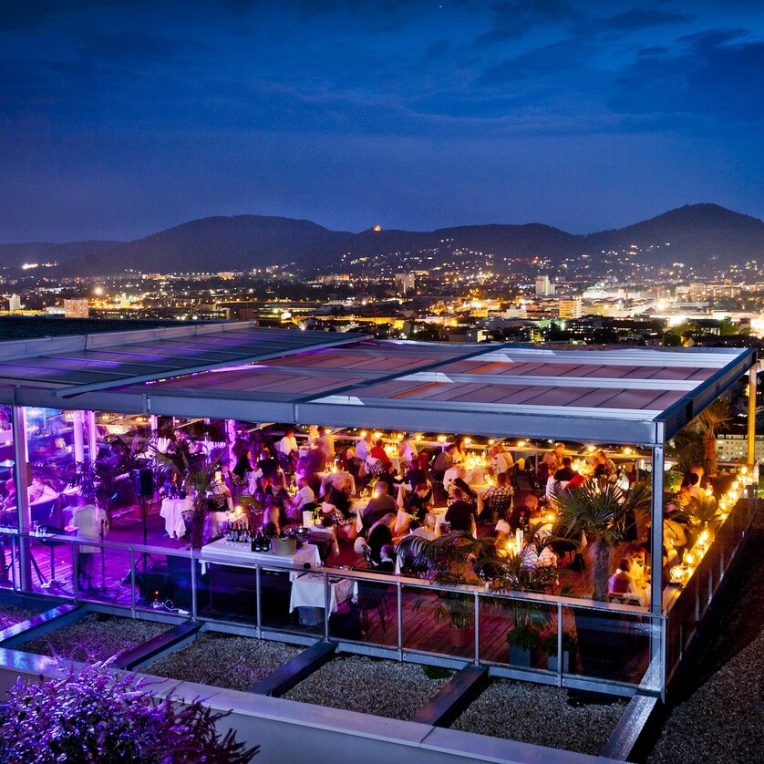 Illuminated rooftop restaurant in Graz at night. | © Werner Krug
