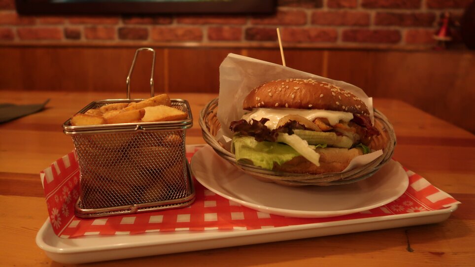 Ein saftiger Burger mit Beilagen auf einem Teller.