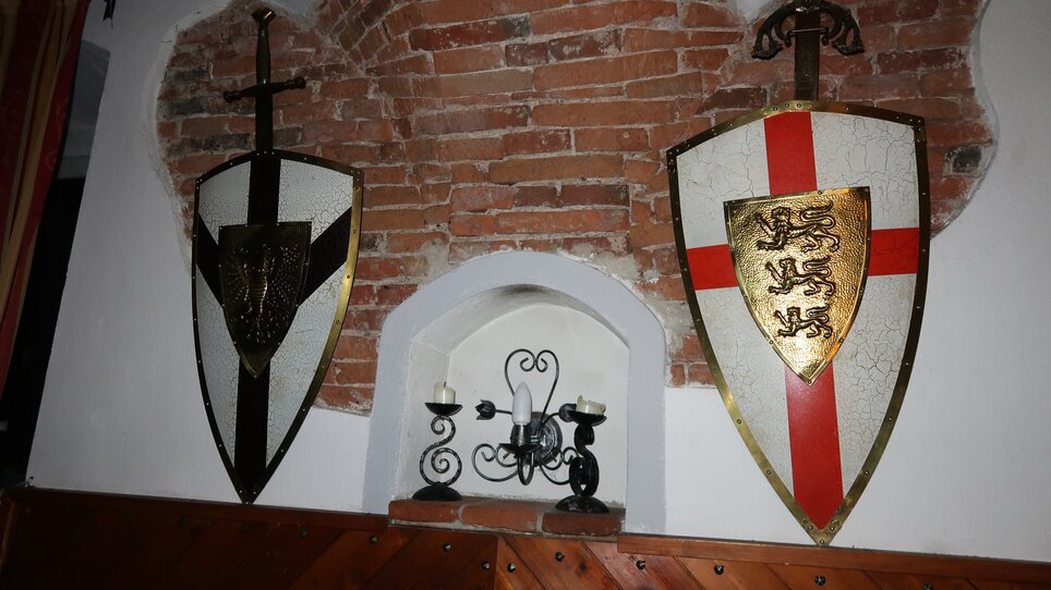 Zwei dekorative Wappenschilder an einer Ziegelwand im Ritterwirt Graz.
