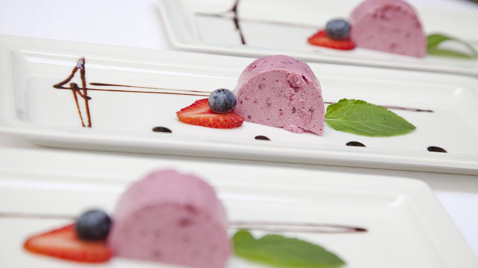 Dessert con mousse di bacche, fragole e menta sul piatto. | © Gasthaus Stainzerbauer