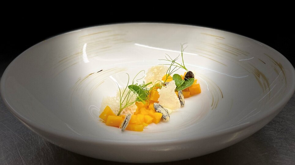 A beautifully plated dish featuring mango, garnish, and herbs. | © Julian Wallner