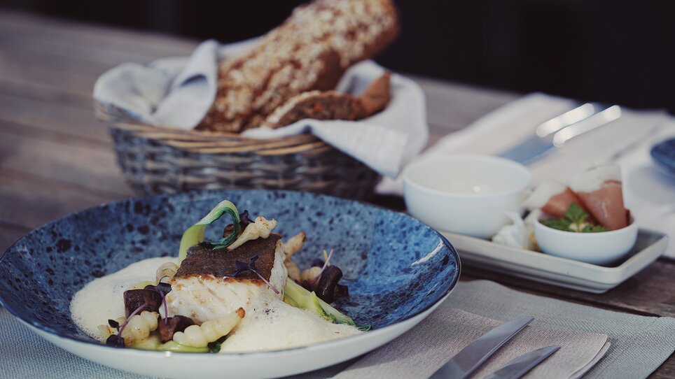 Un piatto di pesce artisticamente presentato con contorni. | © aiola