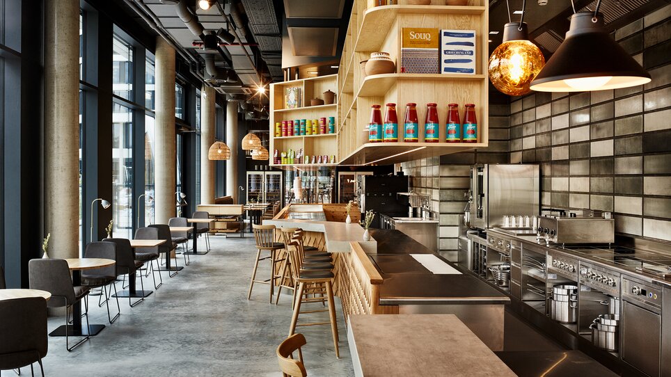 Interno moderno di un ristorante con area bar e cucina a vista.