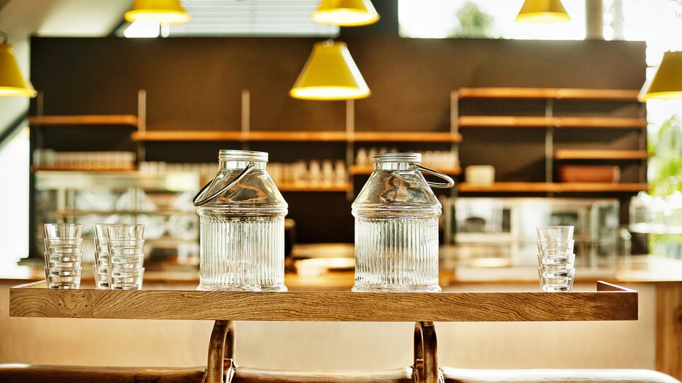 Due brocche di vetro con bicchieri su un vassoio di legno in un caffè.