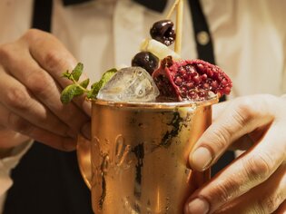 Ein Barkeeper dekoriert einen Cocktail in einem Kupferbecher. | © Magdalena Bereźnicka