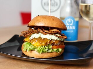 Hamburger succulento con formaggio, lattuga e anelli di cipolla su un piatto. | © Burger Factory
