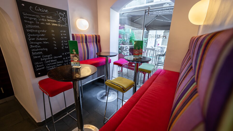 Un caffè moderno a Graz con sedie colorate e un menu di vini. | © Ripix