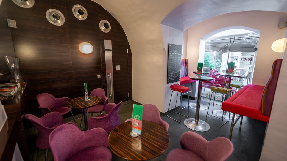 Interno moderno con sedie viola e tavoli in legno. | © Ripix