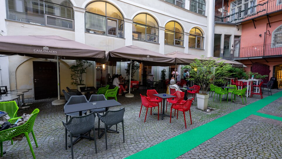 Cortile accogliente con sedie e tavoli colorati a Graz. | © Ripix