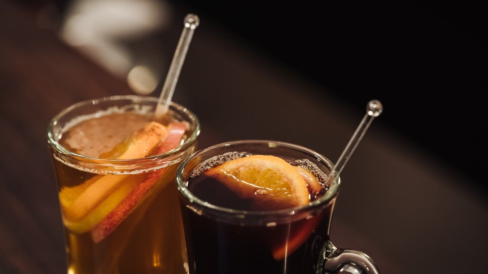 Due bicchieri di bevande calde con fette di frutta in luce soffusa. | © Ripix