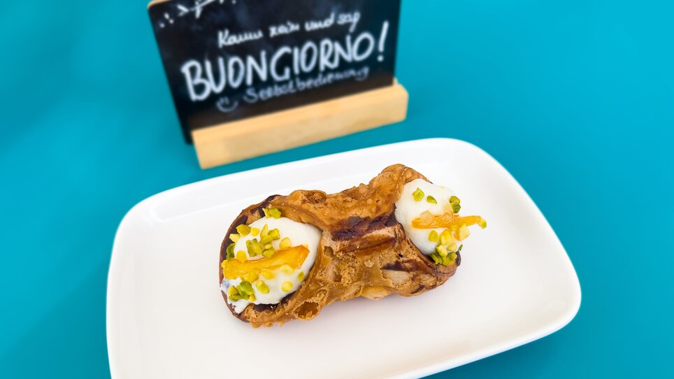 Ein köstliches Dessert mit einer Tafel im Hintergrund, die 'Buongiorno!' sagt. | © Caramello Caffè