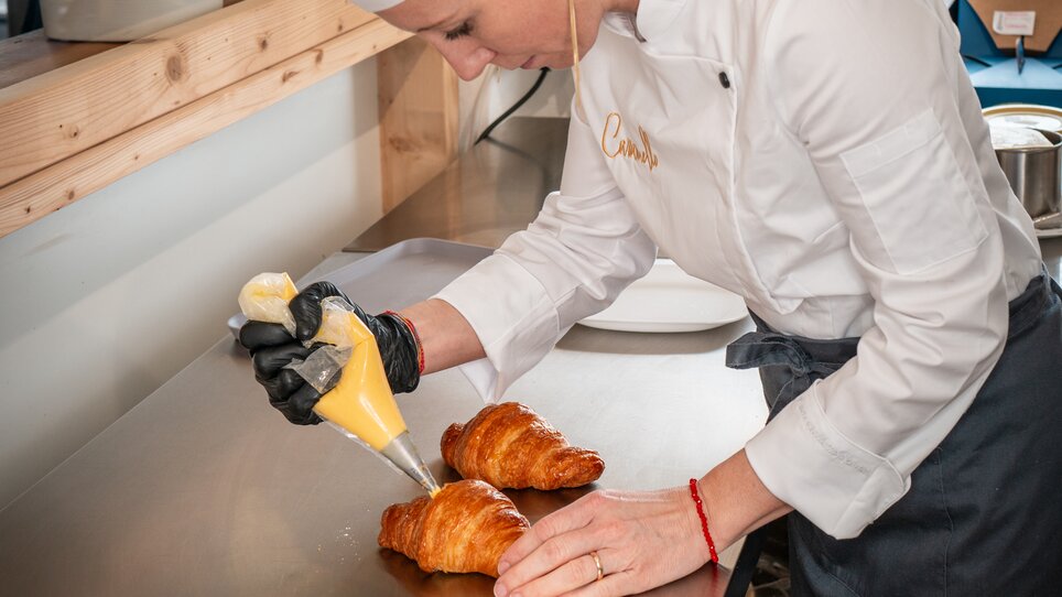 Eine Köchin dekoriert Croissants in einer modern gestalteten Küche. | © Bernd Grosseck