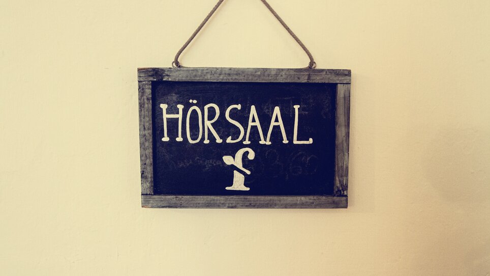 Ein Schild mit der Aufschrift 'HÖRSAAL' und einer stilisierten Zeichnung. | © Cafe Fotter