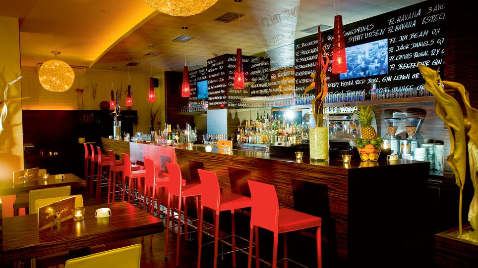 Modern bar with colorful chairs and illuminated counter. | © Cafe Glockenspiel