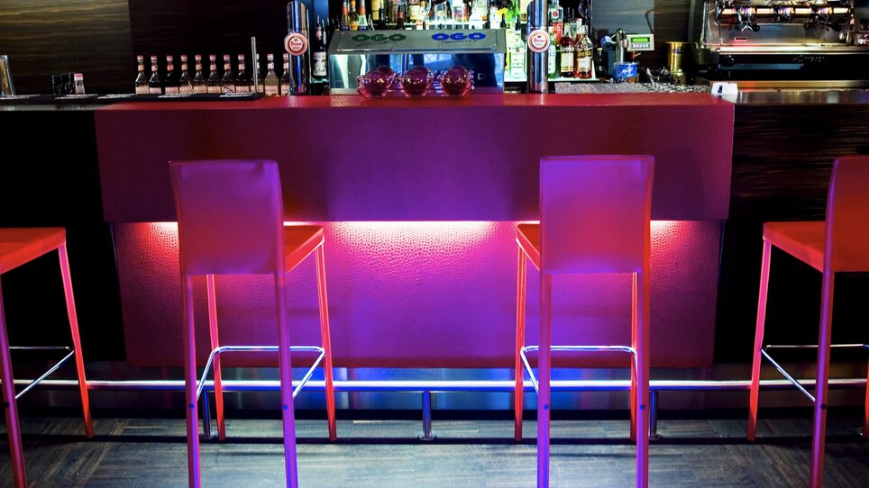 Stylish bar with glowing high tables and drink shelves. | © Cafe Glockenspiel