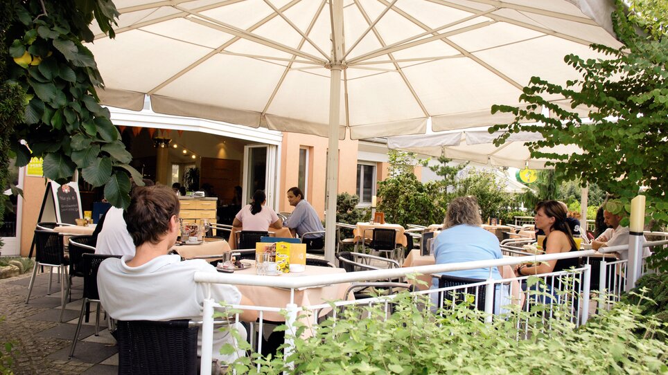 Gemütliches Café mit Terrasse in Graz, Gäste genießen Essen und Trinken unter einem Sonnenschirm. | © Cafe Polanz