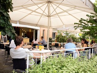 Gemütliches Café mit Terrasse in Graz, Gäste genießen Essen und Trinken unter einem Sonnenschirm. | © Cafe Polanz