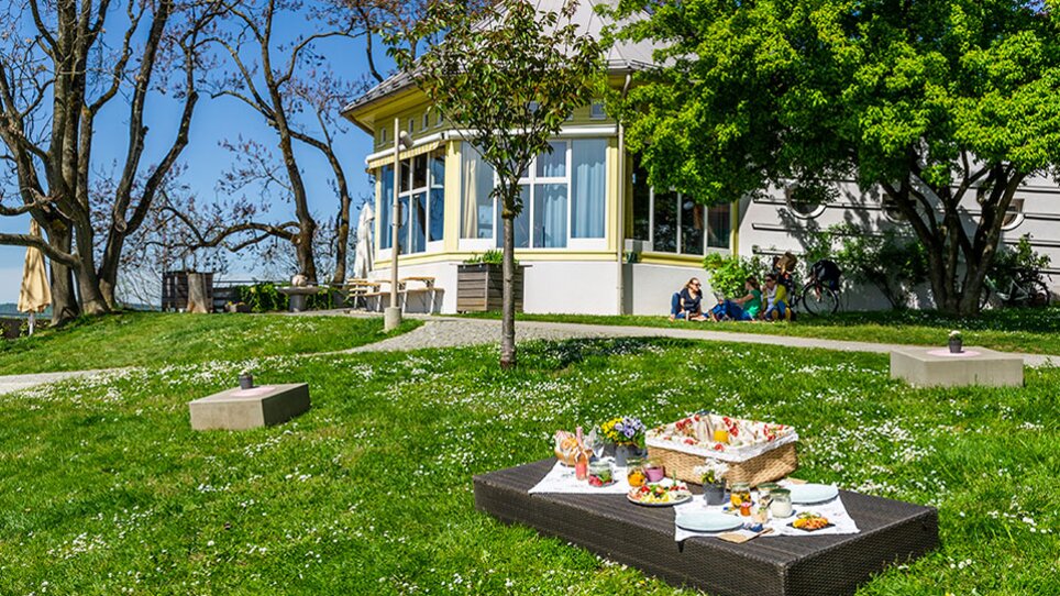 Eine sonnige Wiese mit einem Picknickkorb vor einem Café in Graz. | © Cafe Rosenhain