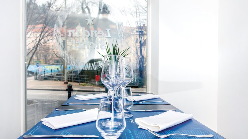 Table setting in Caylend with glasses and plants, view of the street. | © Michael Fiedler