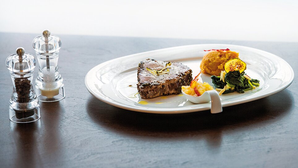 A plate with marinated fish, side dishes, and spice grinders. | © Michael Fiedler