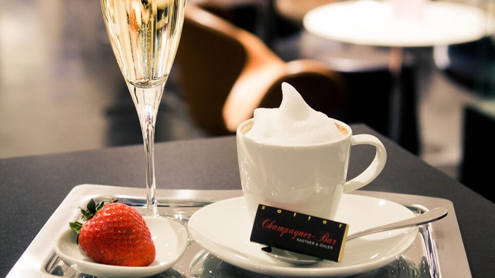 A tray with champagne, coffee, and strawberry in an elegant bar. | © Tageskaffee Freiblick 