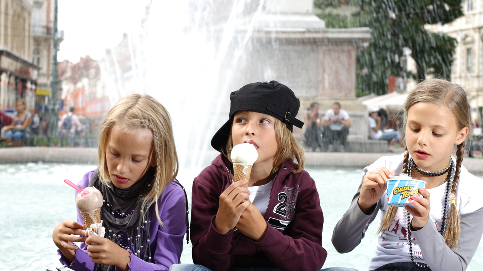 Three kids enjoy ice cream in front of a fountain in Graz. | © Graz Tourismus - Harry Schiffer