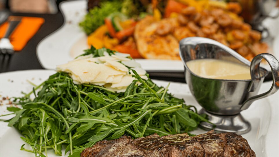 A juicy steak with fresh arugula and cheese, served with a sauce. | © Clocktower