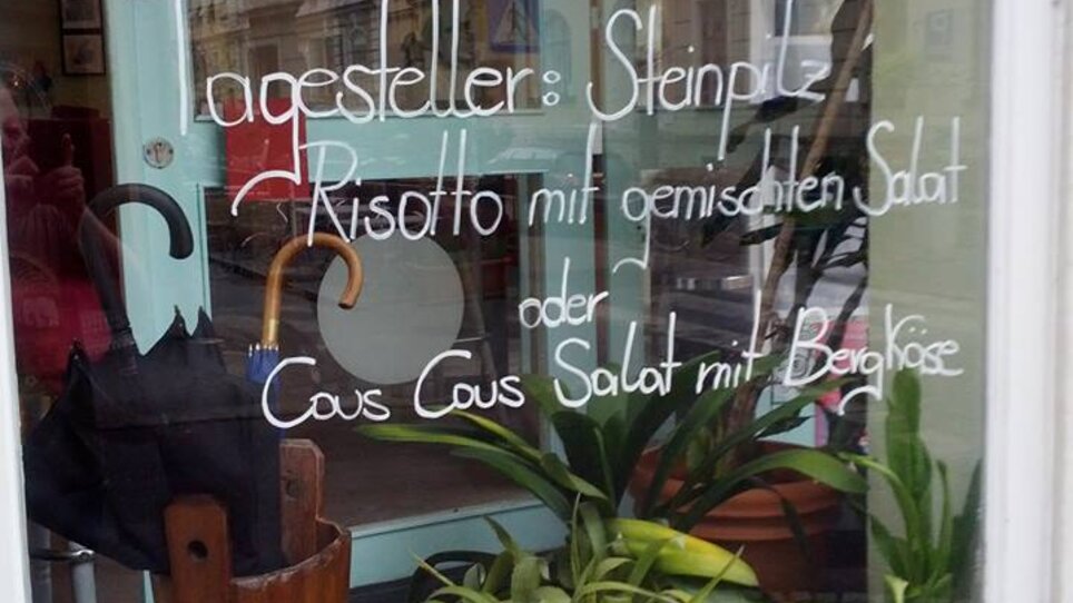Speisekarte im Fenster mit Risotto und Cous Cous-Salat. | © cofeba