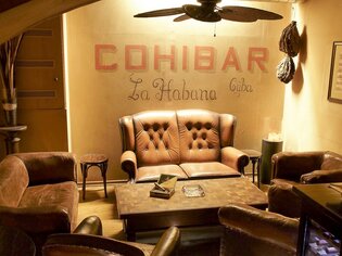 Gemütlicher Loungebereich in der Cohibar mit Ledersofas und einer Wand mit dem Schriftzug 'Cohibar La Habana Cuba'. | © cohibar