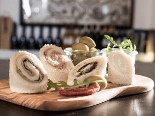 Feine Wraps mit Oliven auf einem Holzbrett. | © Cosimo