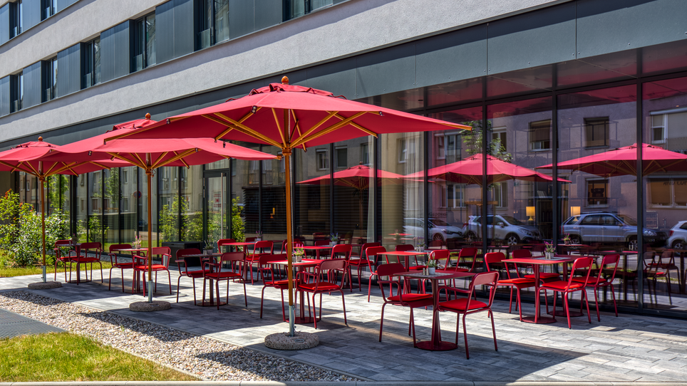 Terrace with red umbrellas and chairs at the IntercityHotel Graz. | © IntercityHotel Graz