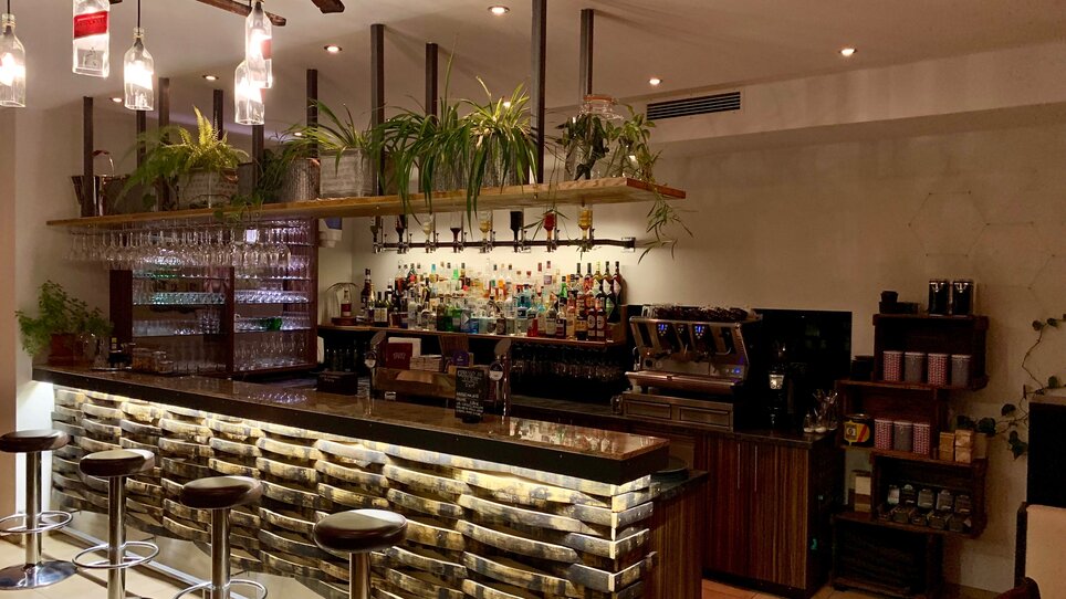 Modern bar with a selection of drinks and plants in the background. | © R&D Gastro OG