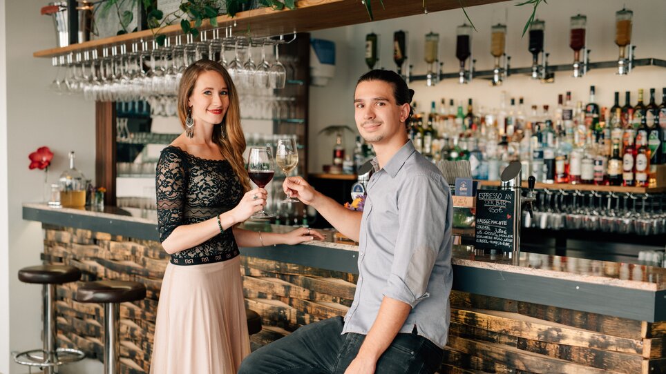 Two people toast with drinks at the bar. | © R&D Gastro OG