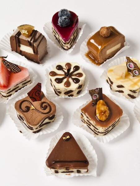 Colorful mini desserts on a white surface, artistically garnished. | © Delikatessen Frankowitsch