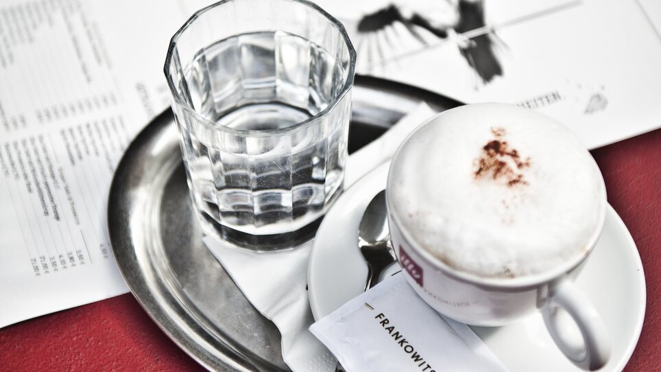Eine Tasse Cappuccino und ein Glas Wasser auf einem Tablett. | © Frankowitsch