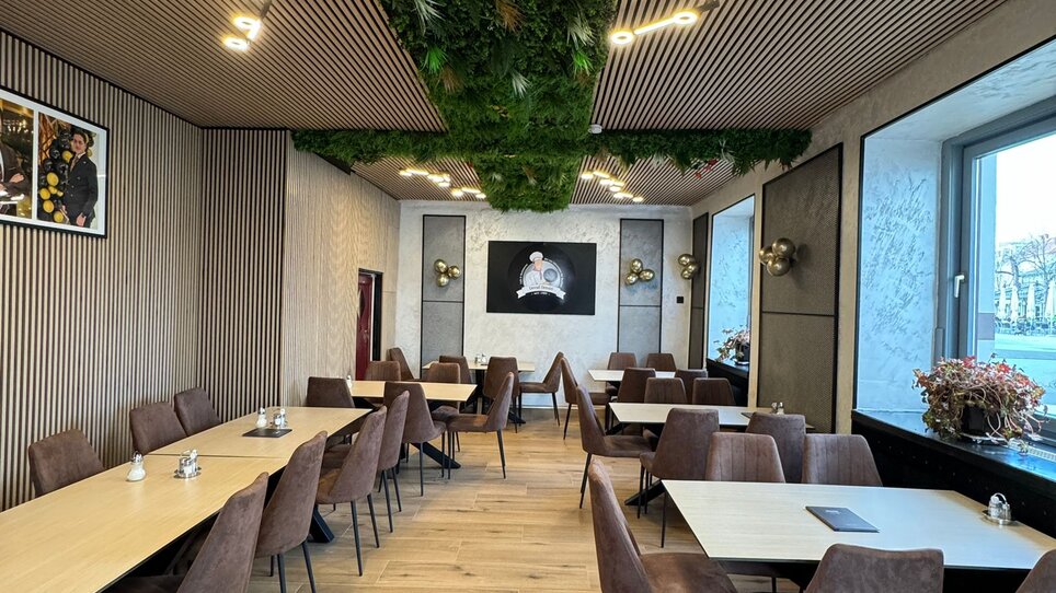 Modernes Café-Restaurant mit Pflanzenwand und eleganten Tischen. | © Demiri