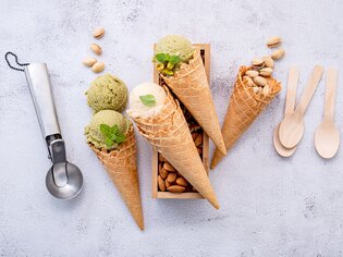 Ice cones with various flavors, surrounded by nuts and spoons. | © Pixabay