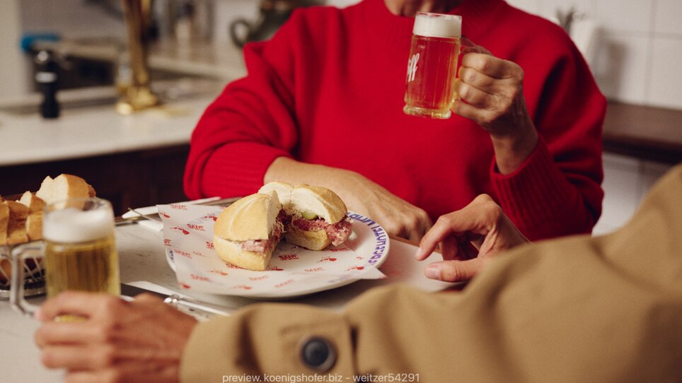 Eine Frau in rotem Pullover mit Bier und Sandwich in Graz. | © Florian Weitzer Hotels und Restaurants