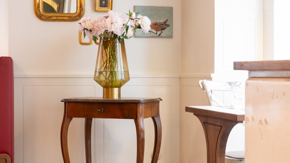 An elegant table with flowers and pictures in a room. | © Florian Weitzer Hotels & Restaurants