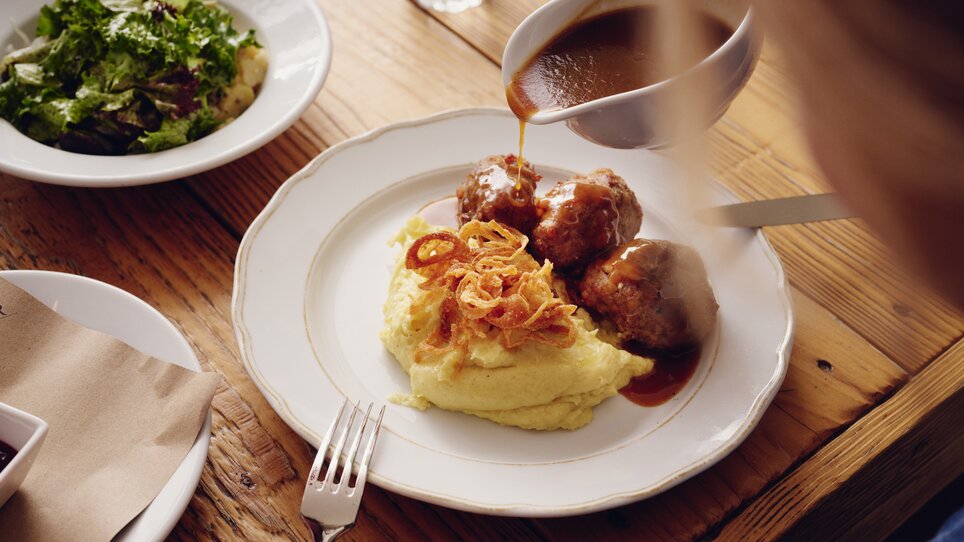 A plate with meatballs and mashed potatoes, next to a salad. | © Florian Weitzer Hotels und Restaurants