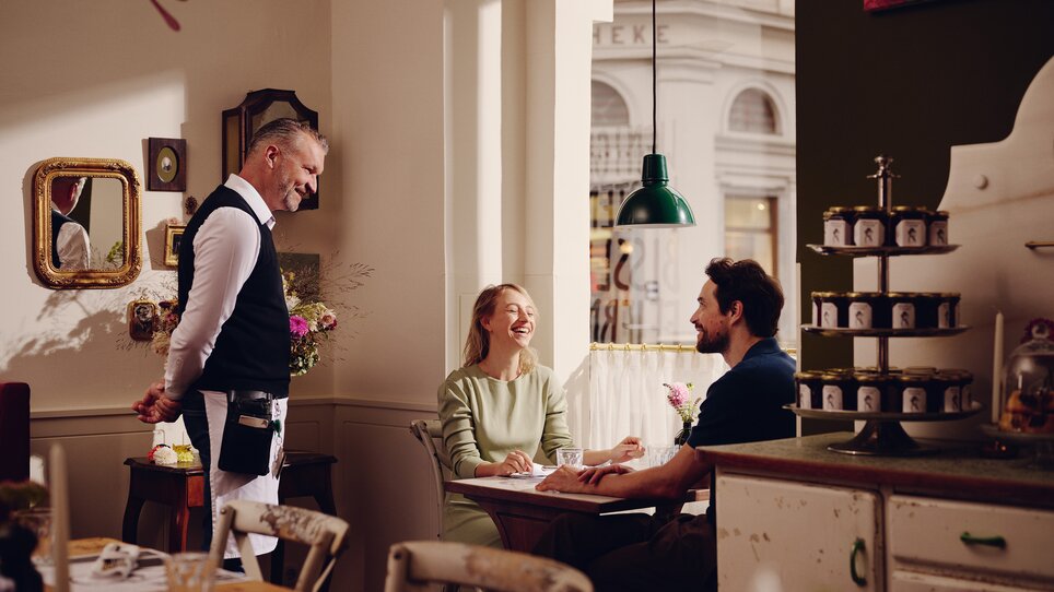 Guests enjoy a meal in a restaurant while being served by the waiter. | © Florian Weitzer Hotels und Restaurants