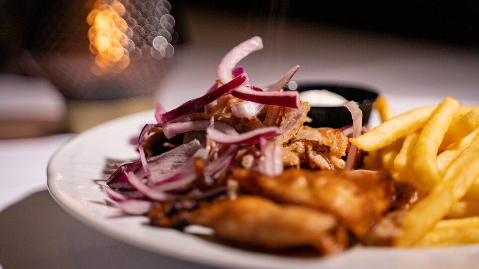A plate with food: fries, meat, and onions. | © Dionysos