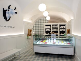Interior of the ice cream shop featuring colorful ice cream and cow sculpture. | © Eis Greissler 