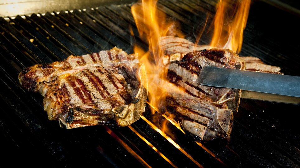 Gegrillte Steaks auf dem Grill mit Flammen. | © El Gaucho - Werner Krug