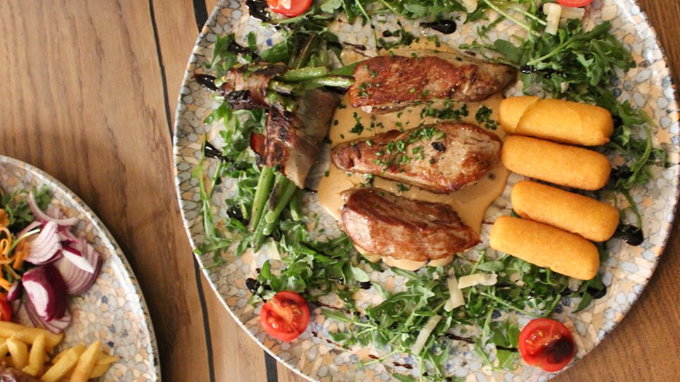 Delicious dish with meat, vegetables, and sides on a plate. | © eleven - idlab Media