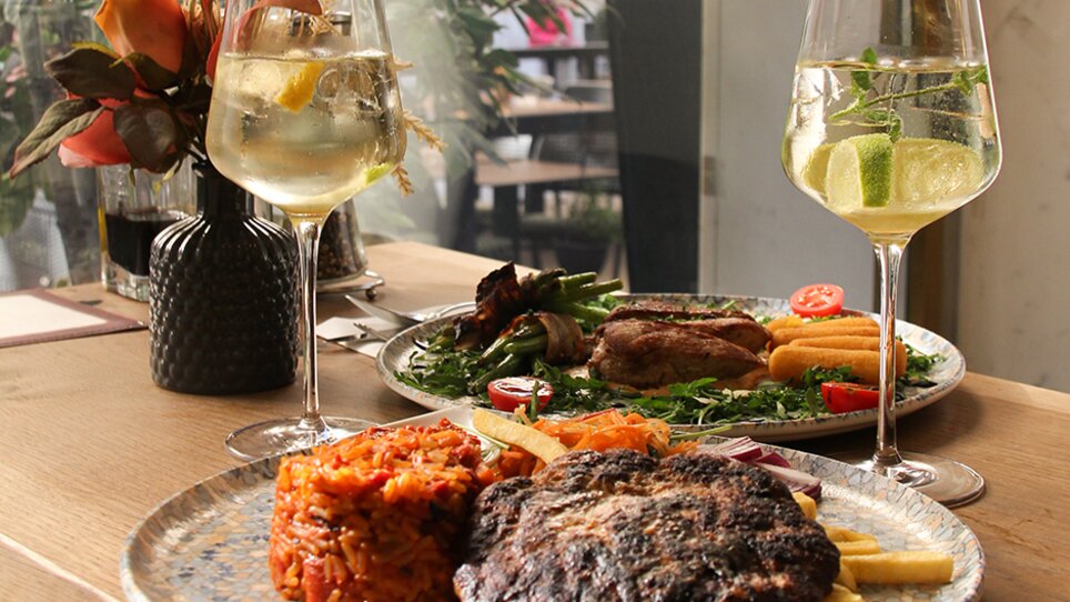 A dish with steak, rice, fries, and cocktails on a table. | © eleven - idlab Media