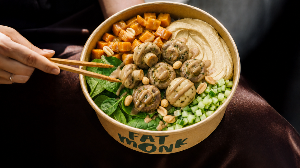 Eine Bowl mit Gemüse und Hummus in einem Karton mit 'FAT MONK' beschriftet. | © Fat Monk – Deli Bowls