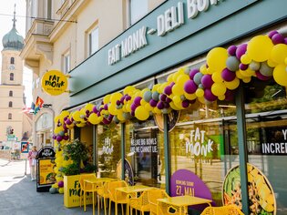Exterior view of FAT MONK Deli Bowls, featuring colourful décor and yellow tables and chairs in the outdoor seating area. | © Fat Monk – Deli Bowls