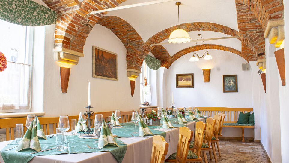 Cozy room with set table and historical brick walls. | © Gasthof Lend-Platzl